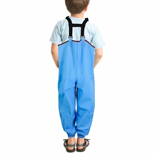 Child wearing blue overalls, back view