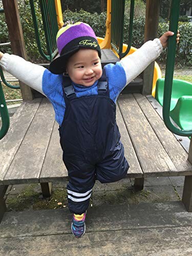 Child in overalls and cap playing on a playground slide.
