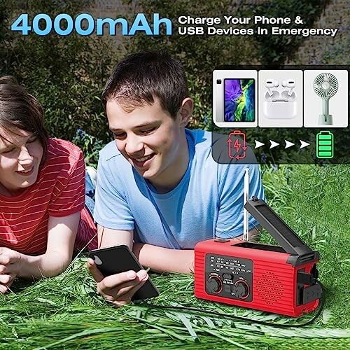 Two people using a red emergency radio with 4000mAh power bank in a grassy area.