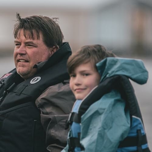 Father and son wearing jackets outdoors.