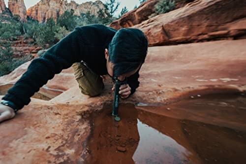 Portable LifeStraw personal water filter being used in a natural setting.