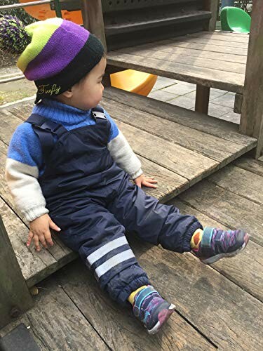 Toddler in winter clothes sitting on wooden steps at playground.